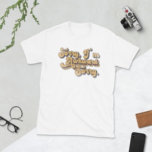 Puede incluir: Camiseta blanca con un gr&aacute;fico de estilo retro que dice "Lo siento, soy torpe Lo siento".