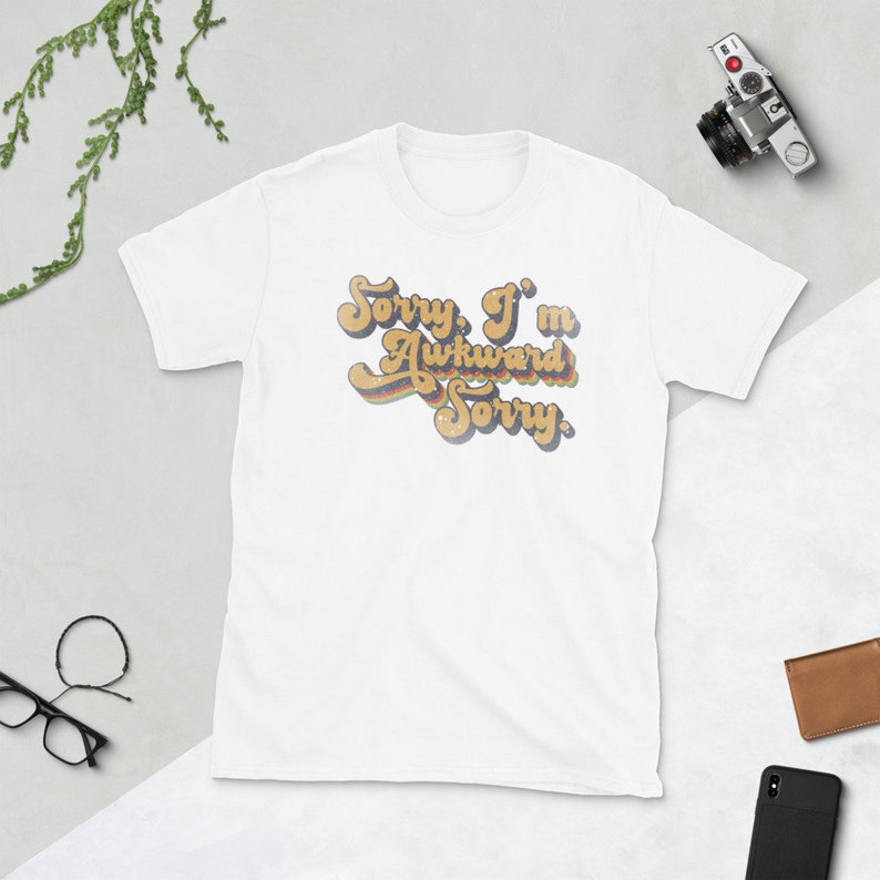 Puede incluir: Camiseta blanca con un gr&aacute;fico de estilo retro que dice "Lo siento, soy torpe Lo siento".