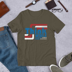 May include: A dark green t-shirt with a red, white, and blue graphic that says "Think While It's Still Legal" with stars.