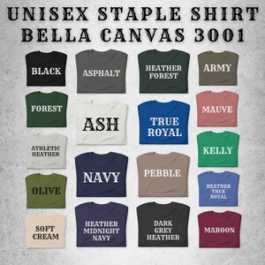 May include: A collection of 16 folded t-shirts in various colors, including black, navy, olive, cream, maroon, and heather grey. Each shirt has a different color and text printed on the front, such as "Black", "Ash", "True Royal", "Navy", "Heather Midnight Navy", and "Dark Grey Heather".