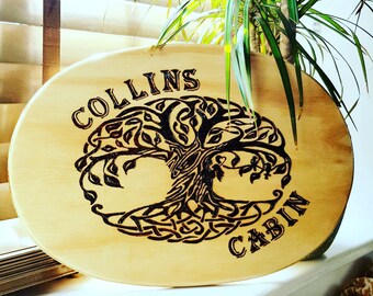 以下が含まれることがあります： 木の看板に生命の木のデザインと「COLLINS CABIN」の文字が焼印されています。