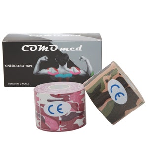 Op de afbeelding: Twee rollen roze en groene camouflage kinesiologie tape. De tape is 5 cm breed en 5 m lang. De doos heeft de tekst "COMD med Kinesiology Tape 5cm X 5m 2 ROLLS" en toont een afbeelding van een persoon met tape op de rug.