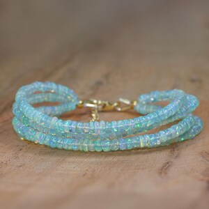 May include: A delicate bracelet made with multiple strands of light blue opal beads. The bracelet has a gold clasp.