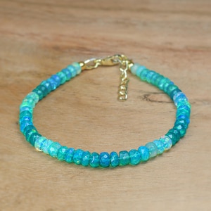 May include: A delicate bracelet made with graduated opal beads in shades of light blue and green. The bracelet has a gold clasp and is approximately 7 inches in length.
