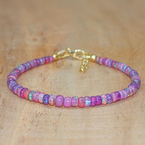 May include: A delicate bracelet made with small, iridescent pink opal beads and a gold clasp.