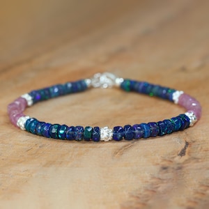 Könnte beinhalten: Ein blaues und pinkfarbenes Edelstein-Armband mit silbernen Akzenten. Das Armband besteht aus kleinen, runden Perlen und hat einen zarten, femininen Look.