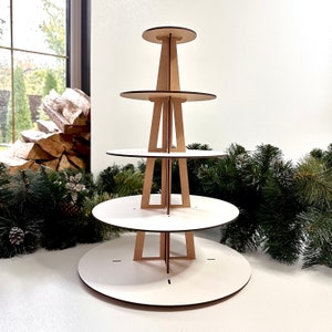 May include: A white four-tiered cupcake stand made of wood. The stand is designed to hold cupcakes or other small desserts. It is a great way to display your baked goods at a party or event.