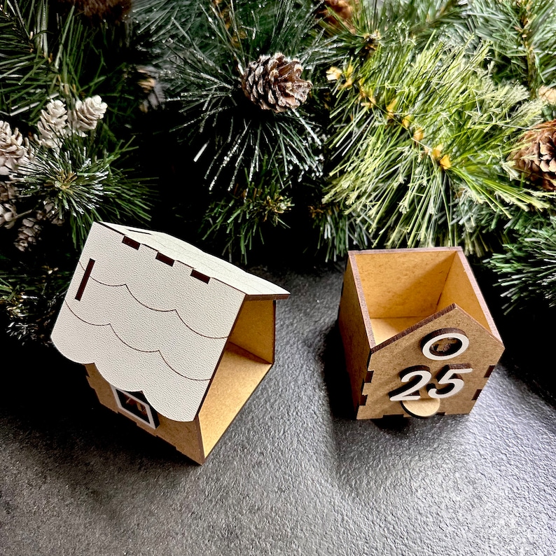May include: A wooden Christmas advent calendar shaped like a house with a white roof. The calendar has a small door with the number 25 on it.