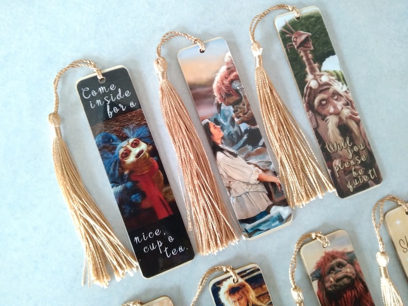 K&ouml;nnte beinhalten: Satz von acht Lesezeichen mit Figuren aus dem Film Labyrinth. Jedes Lesezeichen zeigt eine andere Figur und ein Zitat aus dem Film. Die Lesezeichen sind aus stabilem Karton und haben einen goldenen Quasten.