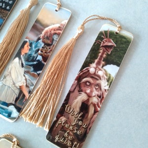 K&ouml;nnte beinhalten: Set von drei Lesezeichen mit Figuren aus dem Film Labyrinth. Jedes Lesezeichen zeigt eine andere Figur und einen goldenen Quasten. Das Lesezeichen mit der Figur des Goblin-K&ouml;nigs sagt "Willst du bitte ruhig sein!"