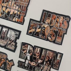 May include: Set of nine black and white stickers with movie quotes and images. The stickers feature quotes like "Most Men Lead a Little Practice", "Ladies First", "Run Down the Hall", and "I'm a Big Girl Now".