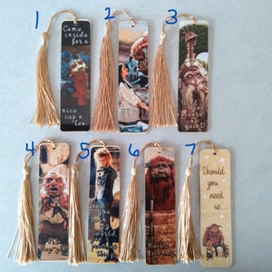 K&ouml;nnte beinhalten: Satz von sieben Lesezeichen mit Figuren und Zitaten aus dem Film Labyrinth. Jedes Lesezeichen hat einen goldenen Quasten. Die Lesezeichen zeigen Figuren wie Jareth, Sarah, Ludo und den Goblin-K&ouml;nig.