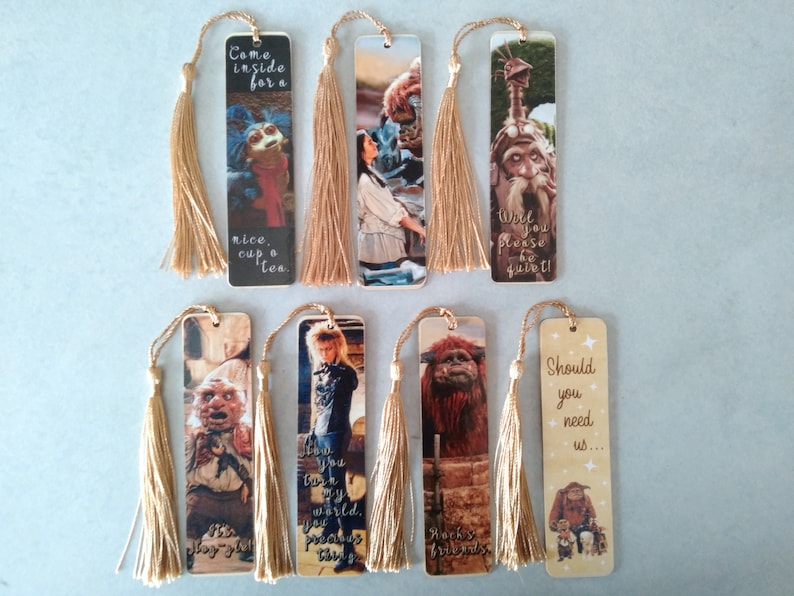 K&ouml;nnte beinhalten: Satz von acht Lesezeichen mit Figuren und Szenen aus dem Film Labyrinth. Jedes Lesezeichen hat einen goldenen Quasten und ein Zitat aus dem Film. Die Zitate sind: "Komm rein zu einer Tasse Tee", "Willst du bitte still sein!", "Wie du meine Welt ber&uuml;hrst, kostbares Ding", "Rocks Freunde", "Solltest du uns brauchen...", "Du erinnerst mich an meine Mutter", "Ich habe keine Angst vor dir", "Du bist ein ganz besonderer Junge".