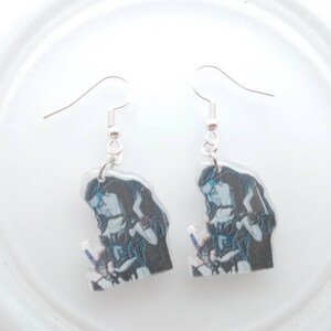 May include: A pair of silver dangle earrings with a clear plastic charm featuring a black and white image of two people embracing.