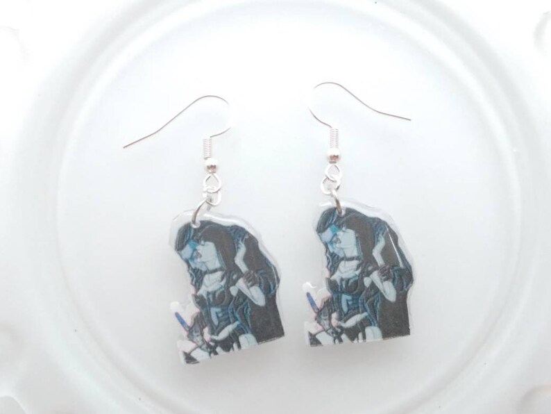 May include: A pair of silver dangle earrings with a clear plastic charm featuring a black and white image of two people embracing.
