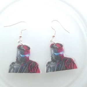 May include: A pair of silver dangle earrings with a red and black image of a ninja warrior on each earring.