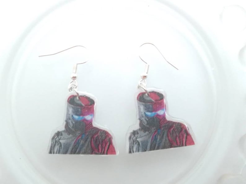 May include: A pair of silver dangle earrings with a red and black image of a ninja warrior on each earring.