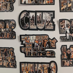 May include: A collection of nine stickers featuring images and text from the movie Clue. The stickers are black with white and yellow text and images. The text on the stickers includes "Never mind about the key, unlock the door", "What?", "Clue", "Practice", "Good's precious", "1+1= not 2", "Go to the other room", "This is such a strange place", and "The rules of the game".
