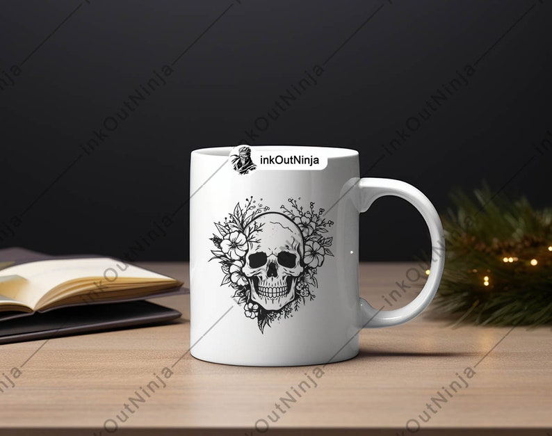 May include: White ceramic mug with a black and white illustration of a skull surrounded by flowers. The mug has a black handle and the text "inkOutNinja" is printed on the side.