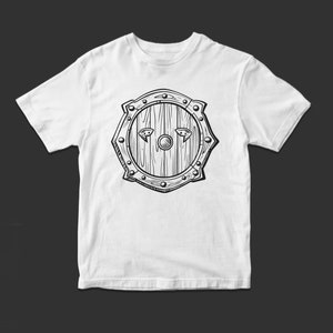 May include: White t-shirt with a black and white illustration of a wooden shield with metal accents.