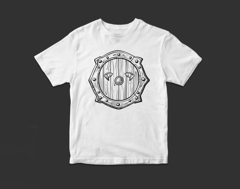 May include: White t-shirt with a black and white illustration of a wooden shield with metal accents.
