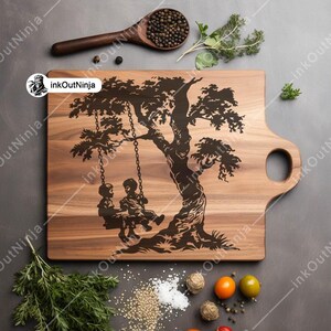 May include: A wooden cutting board with a carved design of a tree with two children on a swing. The board has a handle on the side.