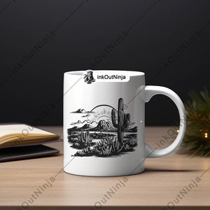 May include: White ceramic mug with a black and white illustration of a desert landscape with a cactus and mountains. The sun is rising over the mountains.