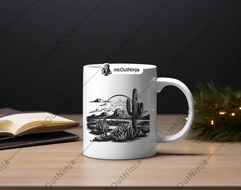 May include: White ceramic mug with a black and white illustration of a desert landscape with a cactus and mountains. The sun is rising over the mountains.