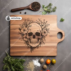 May include: A wooden cutting board with a hand-carved design of a skull with flowers. The board has a handle on the side.