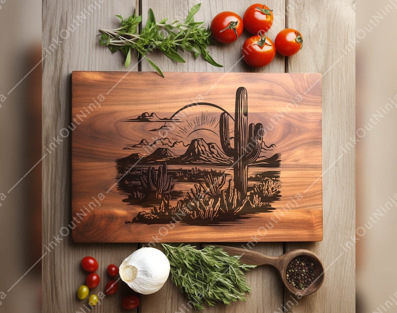 May include: A wooden cutting board with a laser-engraved design of a desert landscape with a cactus and a mountain range. The sun is setting behind the mountains.
