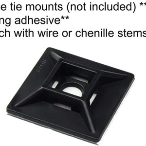May include: Black plastic cable tie mount with adhesive backing. The mount has a square shape with a hole in the center and four smaller holes around the edges. The text "MZ24" is printed on the mount.