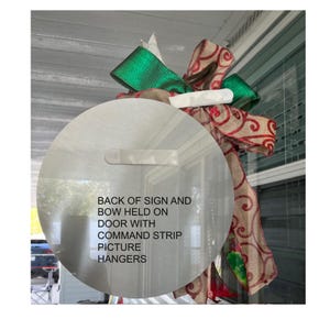 a sign with instructions on how to hang a sign on a door, with a bow and a picture hanger attached to it.
