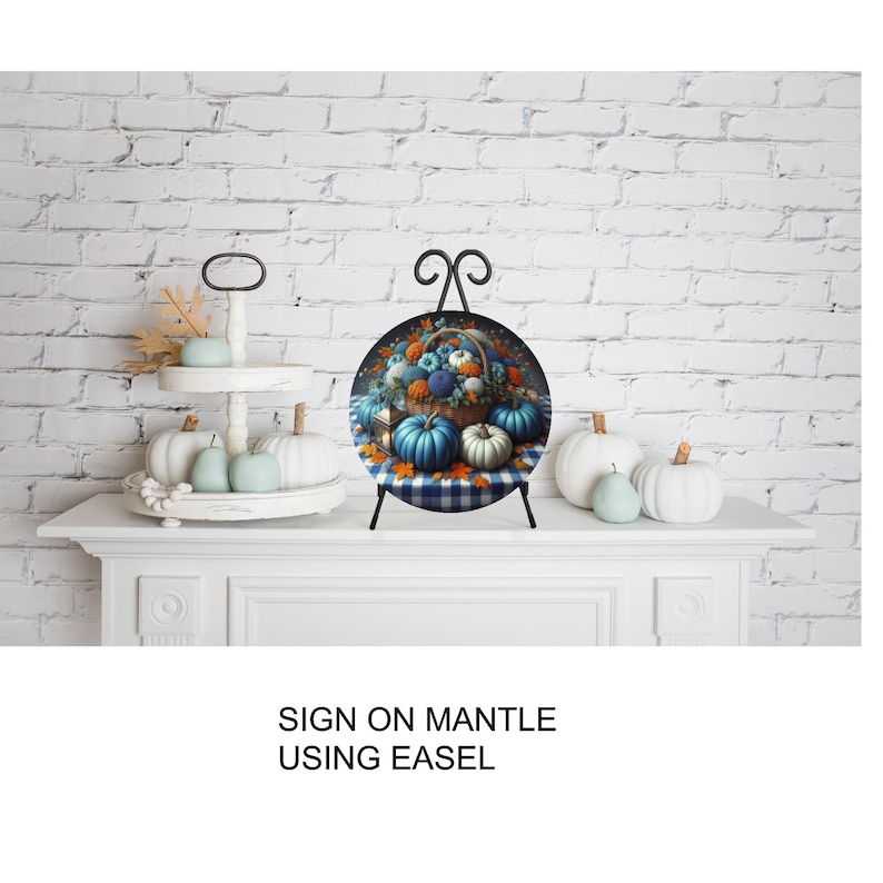 A decorative arrangement of pumpkins and fall foliage on a white mantelpiece, with a sign that reads "SIGN ON MANTLE USING EASEL".