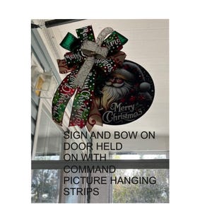 a sign and bow hanging on a door, with the sign displaying a Santa Claus image and the bow featuring a Christmas-themed design.