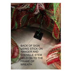 a close-up view of a Christmas wreath made of colorful mesh material, with a black sign attached to it.
