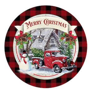 May include: A red truck with a white snowman and a Christmas tree in the back, driving through a snowy winter scene. The truck is in front of a white house with a red roof. The scene is surrounded by a black and red buffalo plaid border with the text "Merry Christmas" in a white banner.