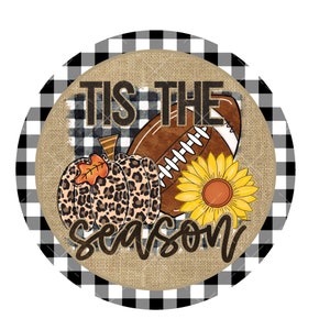 Puede incluir: Un letrero redondo de textura de arpillera con un borde a cuadros blanco y negro. El letrero presenta el texto "Tis the season" con un bal&oacute;n de f&uacute;tbol, un girasol y una calabaza de estampado de leopardo.