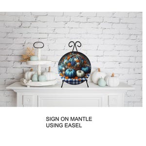A decorative arrangement of pumpkins and fall foliage on a white mantelpiece, with a sign that reads "SIGN ON MANTLE USING EASEL".