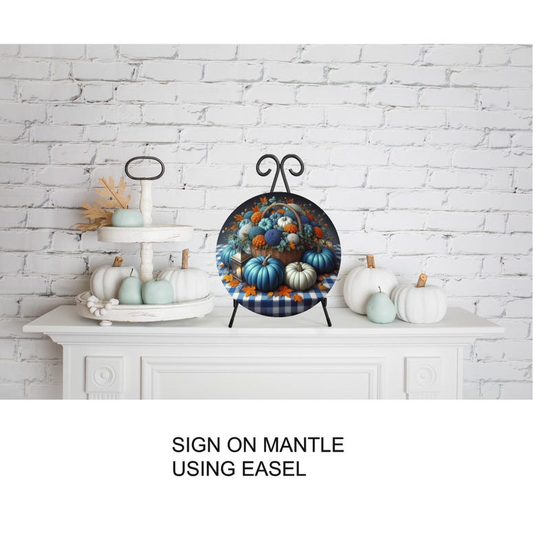 A decorative arrangement of pumpkins and fall foliage on a white mantelpiece, with a sign that reads "SIGN ON MANTLE USING EASEL".