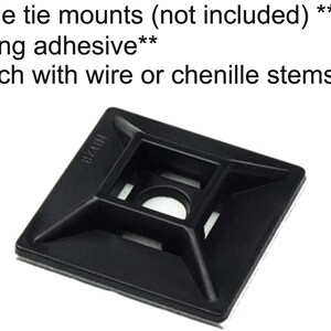 May include: Black plastic cable tie mount with adhesive backing. The mount has a square shape with a hole in the center and four smaller holes around the edges. The text "MZ24" is printed on the mount.