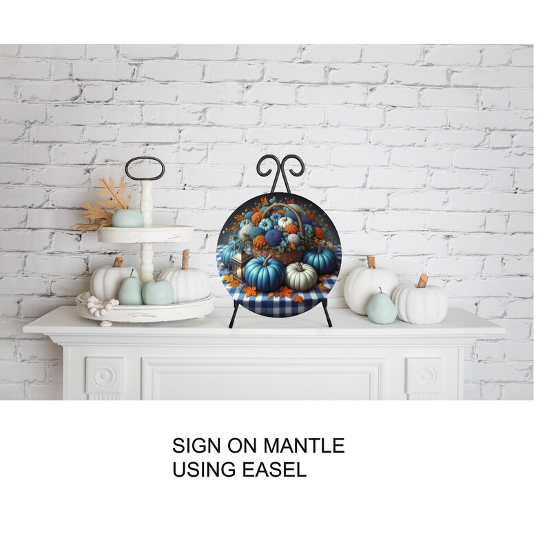 A decorative arrangement of pumpkins and fall foliage on a white mantelpiece, with a sign that reads "SIGN ON MANTLE USING EASEL".