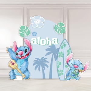 May include: A cartoon cutout set featuring Stitch from Lilo & Stitch. The set includes Stitch playing a ukulele, a surfboard, and a backdrop with the word "aloha" and tropical elements in shades of blue and green.