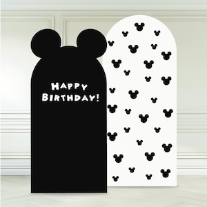 May include: Two decorative party backdrops. One is black with a Mickey Mouse head shape and the words "HAPPY BIRTHDAY!" in white. The other is white with a pattern of black Mickey Mouse heads. Ideal for a birthday party.