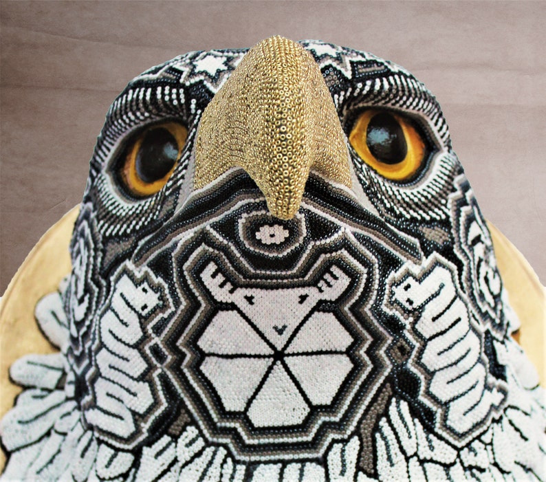 May include: Close-up of a beaded eagle head sculpture with a gold beak and black, white, and gray geometric patterns.