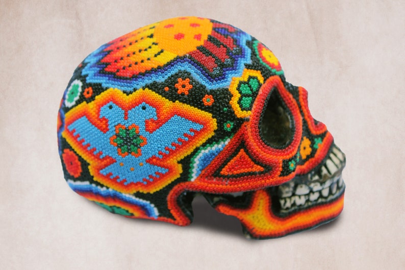 May include: A colorful beaded skull with a detailed design of two birds and flowers. The skull is made of black beads with red, orange, yellow, blue, and green accents.