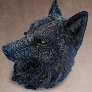 Detailed beaded wolf head sculpture featuring intricate patterns in vibrant shades of blue, green, and purple. The wolf’s striking green eyes create a captivating focal point. Handcrafted with glass seed beads, this textured and dimensional piece brings depth and brilliance to any space. Perfect as wall decor, this Huichol (Wixárika)-inspired artwork blends Mexican folk art, spiritual symbolism, and artisan craftsmanship—ideal for collectors and lovers of unique handmade decor.