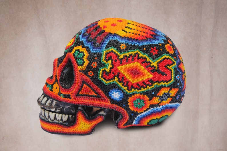 May include: A colorful skull made of beads. The skull is decorated with a variety of geometric and floral patterns in shades of red, orange, yellow, green, blue, and black.