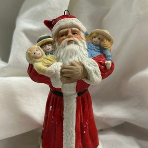 A vintage Christmas ornament of a Santa holding toys d 1988 the ornament may be hung from the tree or sat on a table or shelf,  preowned .
