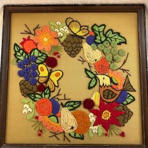 Vintage Crewel Arbeit c 1970er Jahre eine Gartenszene mit Früchten, Blumen, Vogel, Schmetterlingen in einem Holzrahmen in gutem Vintage Zustand gebraucht.