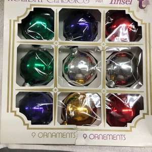 A vintage set of 9 Tinsel glass Christmas tree ornaments mixed colours preowned in good condition in their original presentation box c1960s